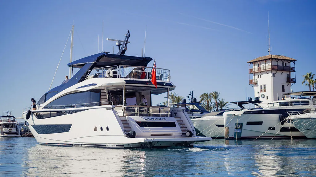 Superyacht JUNIOR am Liegeplatz in Puerto Portals, Mallorca — Heckansicht mit Marina-Promenade, der Standard für anspruchsvolle Liegeplätze auf der Insel