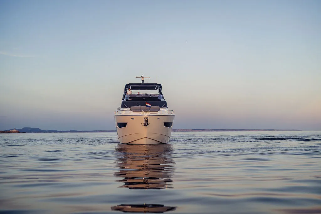 Luxus-Motoryacht JUNIOR im Dämmerlicht vor Mallorca — Bugfront-Ansicht über spiegelglattem Wasser, der Standard für die professionelle Yachtpräsentation beim Verkauf