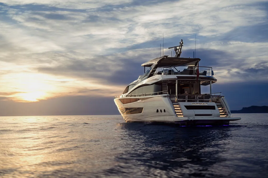 VIP-Dinner an Bord einer Yacht vor Mallorca — Gäste am gedeckten Tisch im warmen Abendlicht der Bucht, ein Eigner-Erlebnis nach dem Yachtkauf