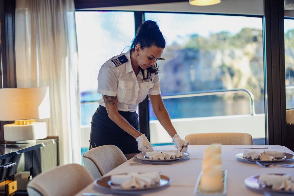 An-Bord-Service auf einer Charter-Yacht — Stewardess deckt den Esstisch im Salon