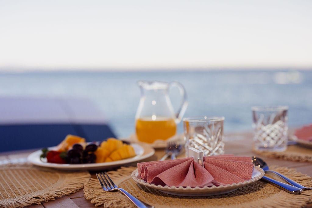 Frühstück an Bord einer Mallorca-Charter-Yacht — Saft, Obst, Esstisch mit Meerblick